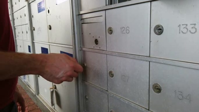 公寓住宅开发中的一个邮箱单元用白人男性的手慢动作拍摄。