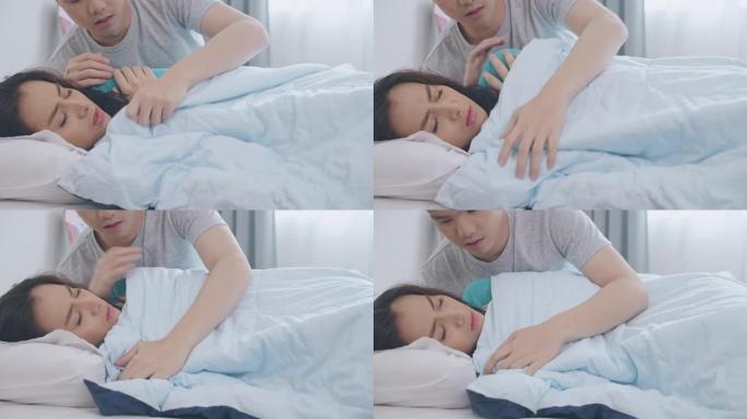 年轻的亚洲男子在床上给女友铺上温暖的毯子。