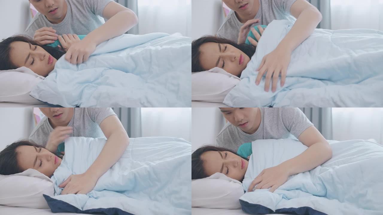 年轻的亚洲男子在床上给女友铺上温暖的毯子。