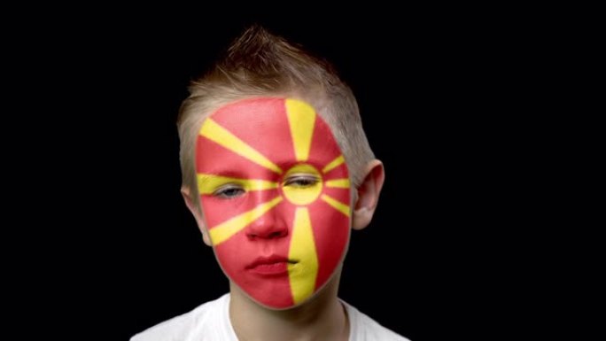 马其顿足球队可悲的球迷。脸上涂着民族色彩的孩子。