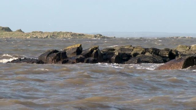 在大风天，苏格兰海滩上的岩石波浪