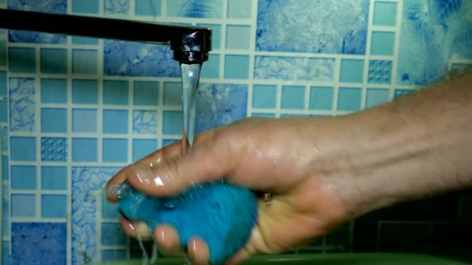 在浴室或厨房的自来水中，人用手洗和冲洗毛巾，用于在自来水下洗碗。