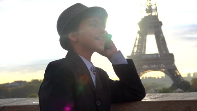 男孩在埃菲尔铁塔的背景下通过电话交谈