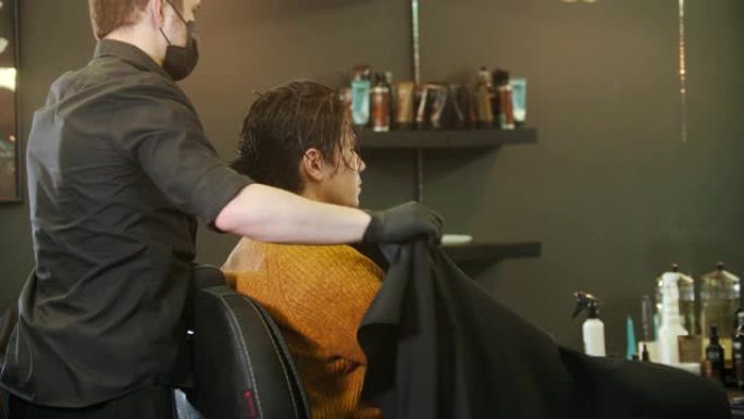 理发师在理发店给他的客户戴上奶桶