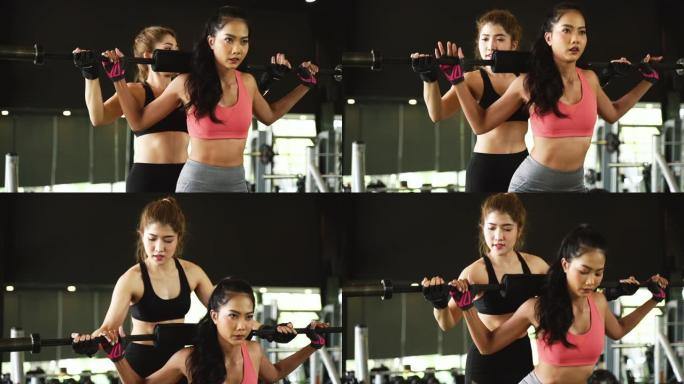 亚洲私人教练指导一名健美女子在健身馆用杠铃进行锻炼。