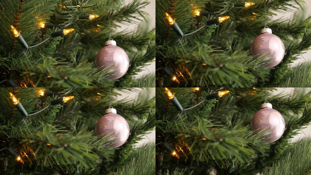 温暖的黄色圣诞灯泡和人造树枝上的粉红色摆设4K