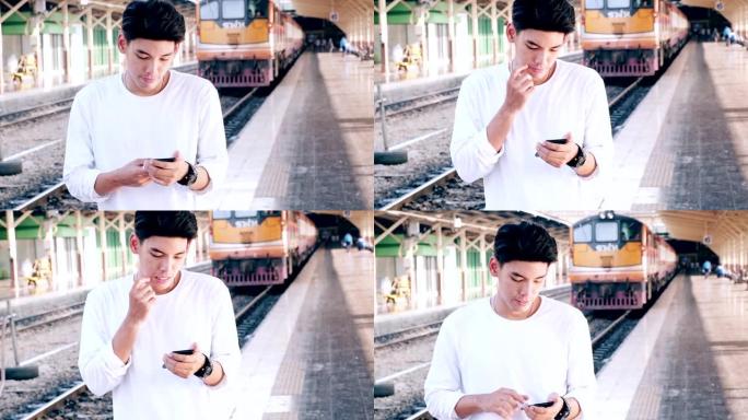 在曼谷火车站等火车的嬉皮士，看着手机，背景是火车。亚洲人。