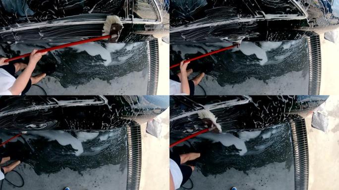 洗车服务中使用泡沫和刷子洗车的男人