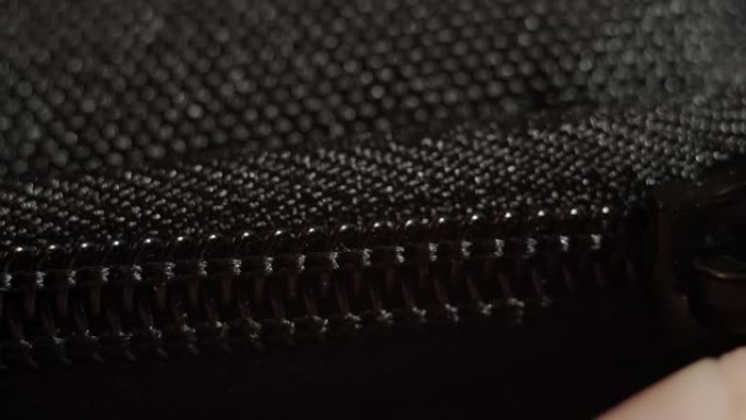 扣上黑色拉链特写。黑色织物材质纹理微距拉链。