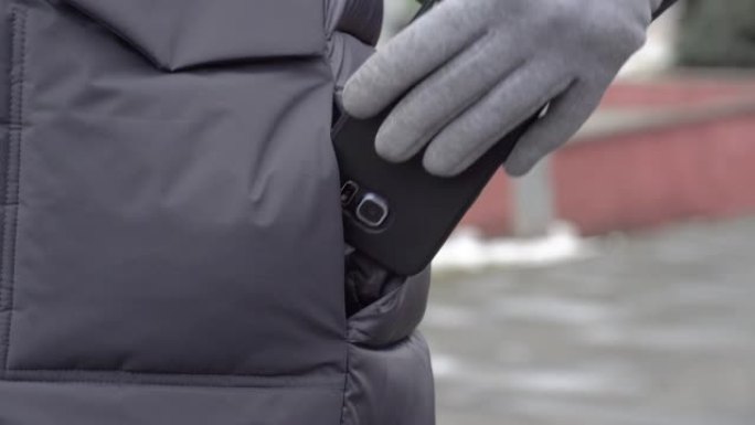 城市街道上的一名妇女从夹克口袋里拿出一部手机。智能手机。