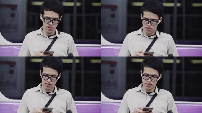 曼谷BTS午夜街市使用智能手机的亚洲男子
