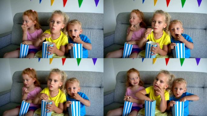 孩子们吃爆米花和看电影。坐在沙发上的小孩