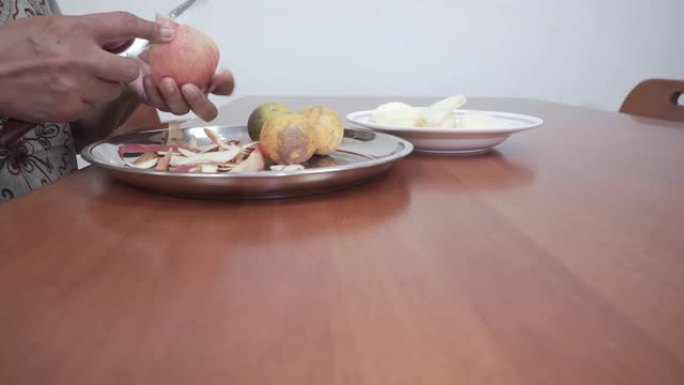 用水果刀在木桌上剥和切割新鲜苹果的手的特写镜头，滑块拍摄