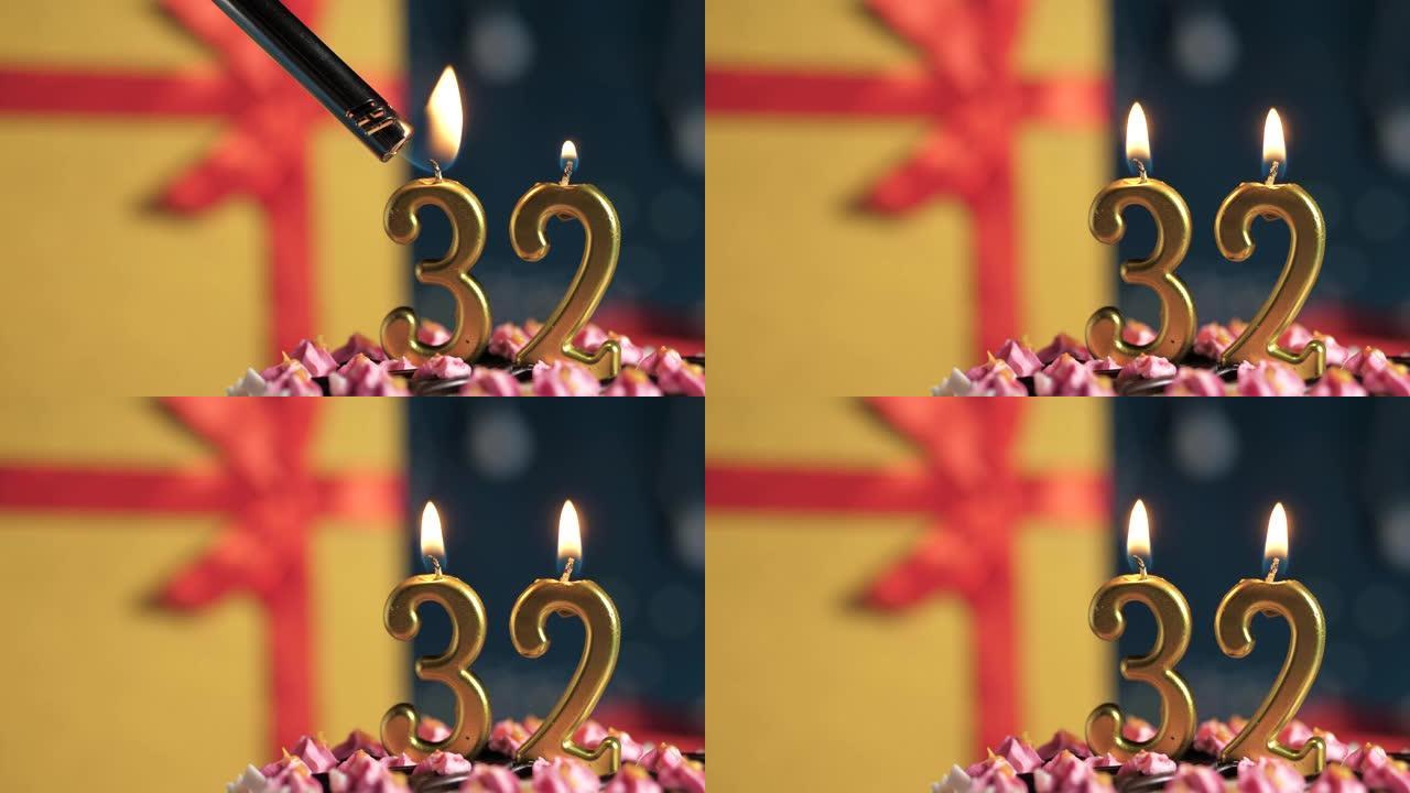 生日蛋糕编号32点灯燃烧的金色蜡烛，蓝色背景礼物黄色盒子用红丝带绑起来。特写和慢动作