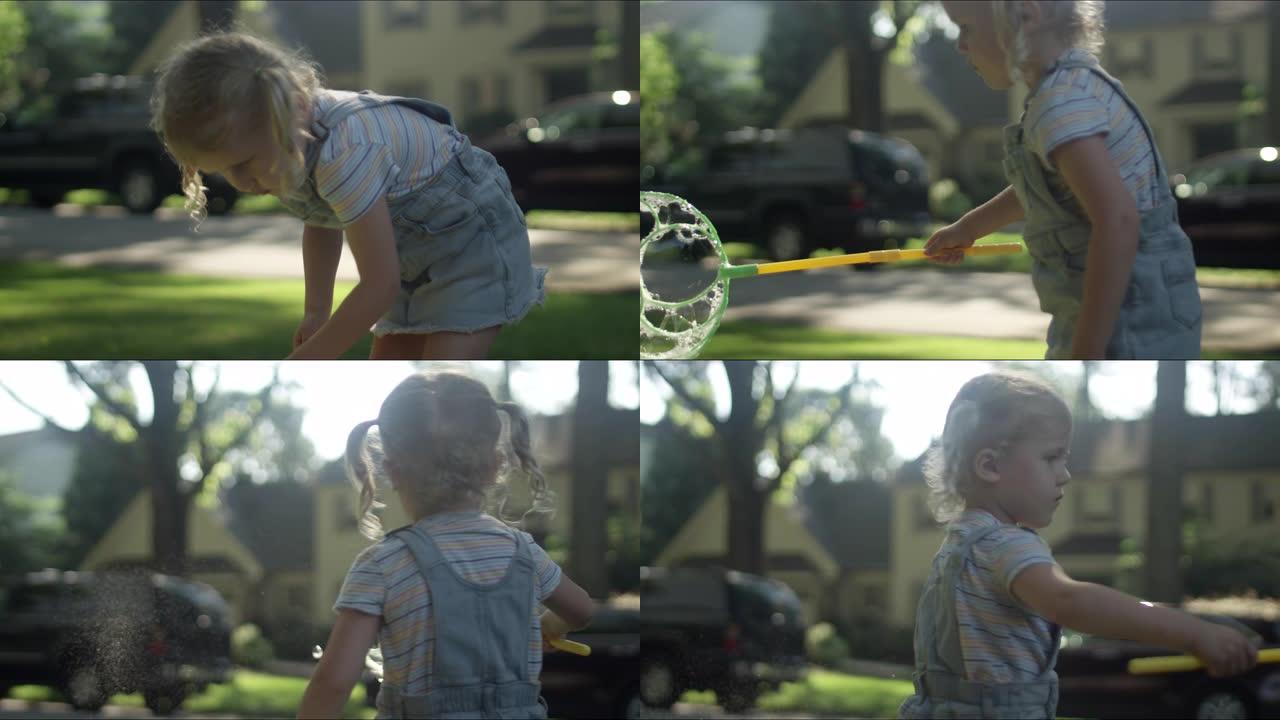 一个可爱的小辫子金发小女孩在院子里用一根大泡泡棒制造泡泡