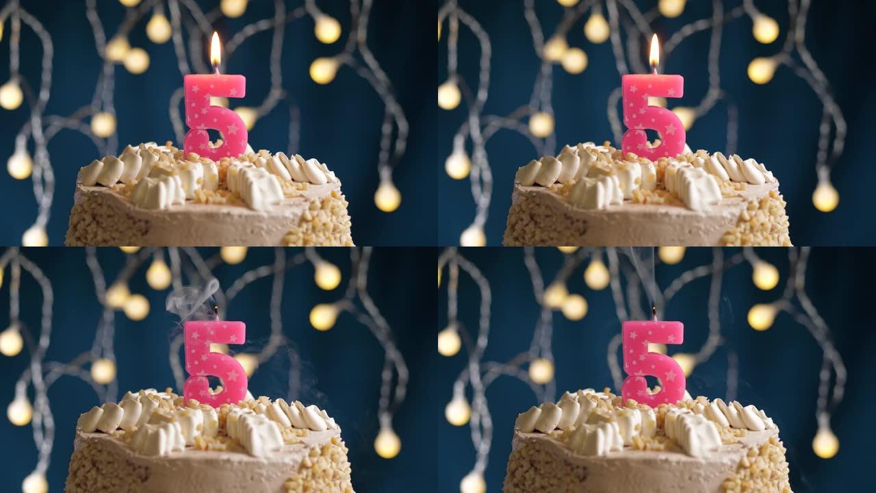 蓝色背景上有5个粉色蜡烛的生日蛋糕。蜡烛吹灭了。慢动作和特写视图