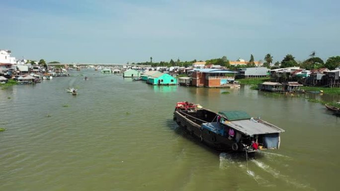 在越南南部的湄公河三角洲，漂浮的Chau Doc村和一艘航行在Bassac河上的船在阳光明媚的美好日