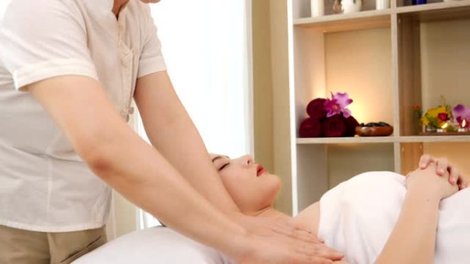 亚洲妇女放松，同时接受一个专业的按摩治疗美容和健康。专业按摩师为亚洲女性按摩后背和肩膀