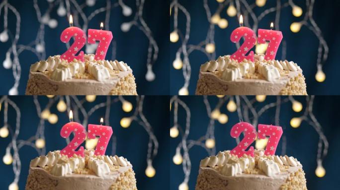 蓝色背景上有27个粉色蜡烛的生日蛋糕。蜡烛吹灭了。慢动作和特写视图