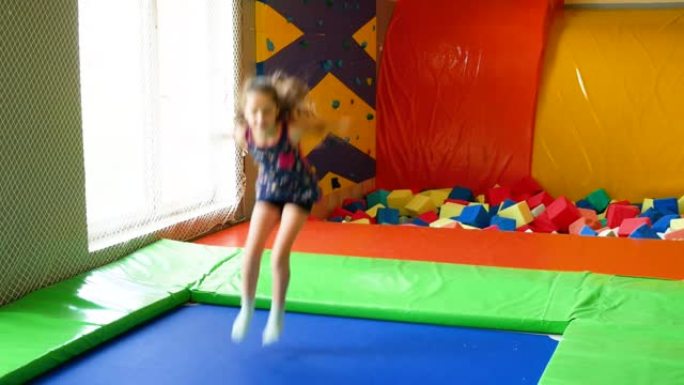 小女孩在游戏中心蹦床和蹦极上跳跃。