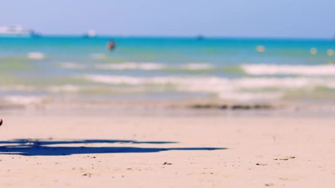 4K UHD假日概念。局部海滩有海浪从海上来到海滩，有人类步行通道。软聚焦和对沙子有选择性的聚焦。