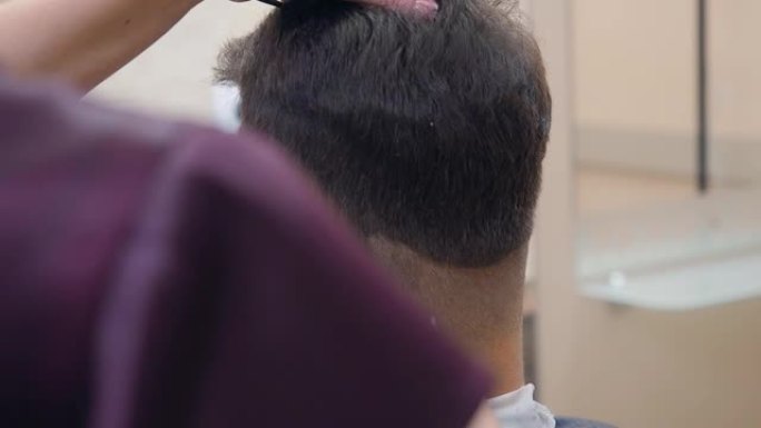 发型师用理发推子和梳子剪头发，近距离拍摄。在理发店记录。海丝沙龙的工作大师。