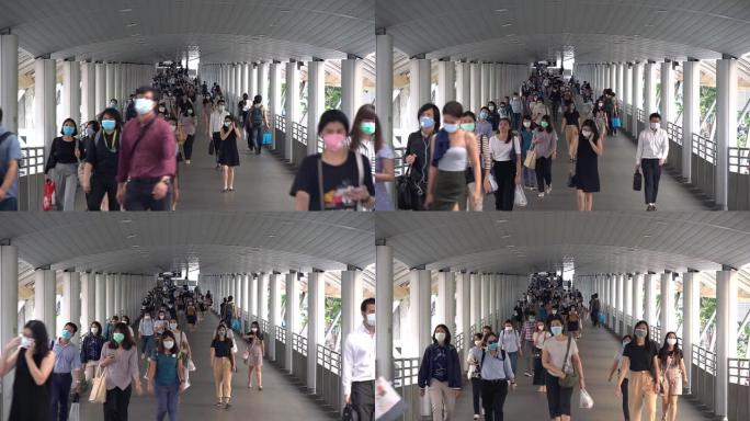 在泰国曼谷Chong-nonsi BTS站的公共交通系统工作人员之后，许多戴着卫生口罩的人在桥梁高峰
