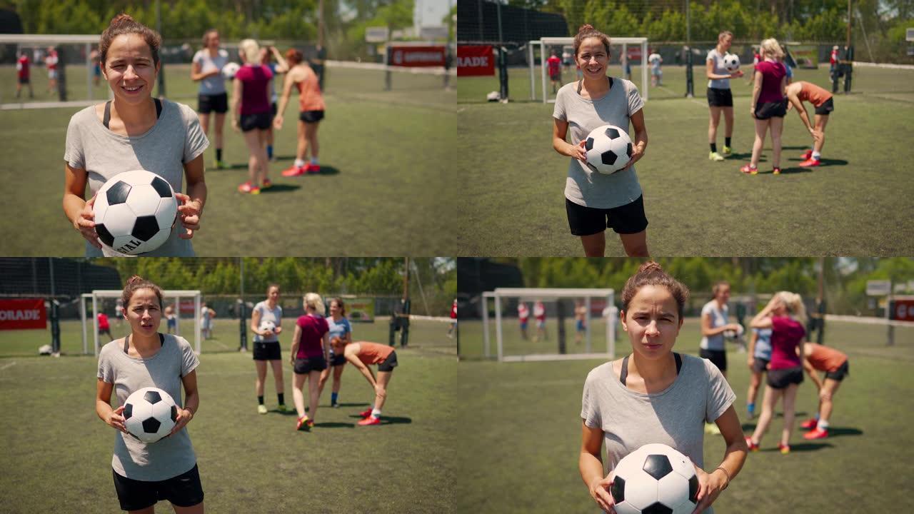 女足球运动员站在足球场上，抱着球