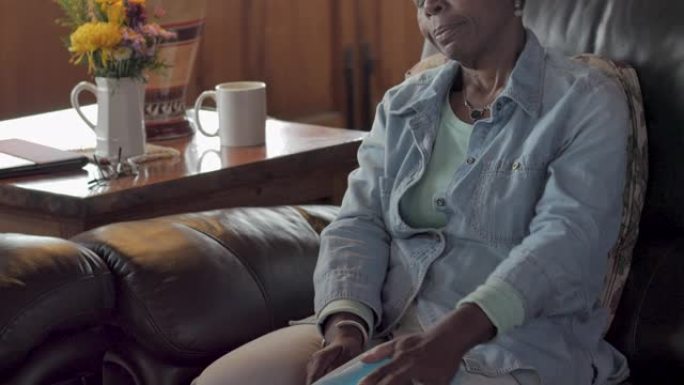 一名老年黑人妇女在膝盖上使用冰袋以缓解疼痛