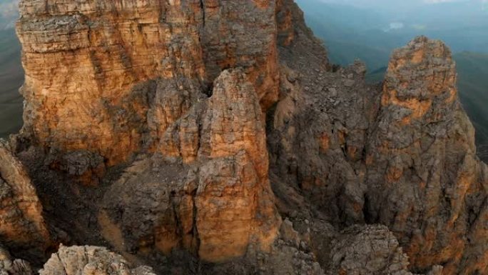 日落时无人机飞越尖锐的岩石露头的鸟瞰图。用于极端登山的陡峭的岩层山。飞行穿越旅行视频