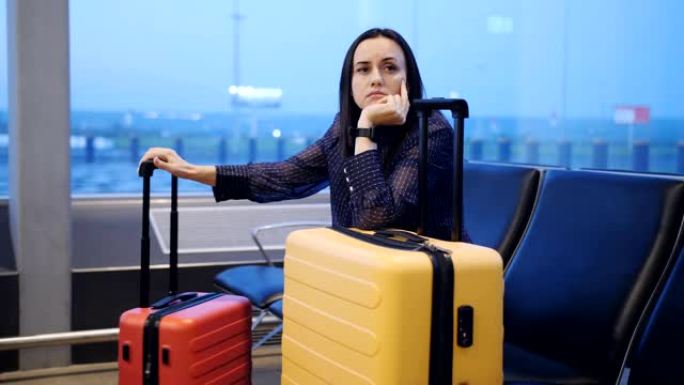 黎明时分，一个无聊的女人带着旅行箱在机场休息室等待航班上的移植。