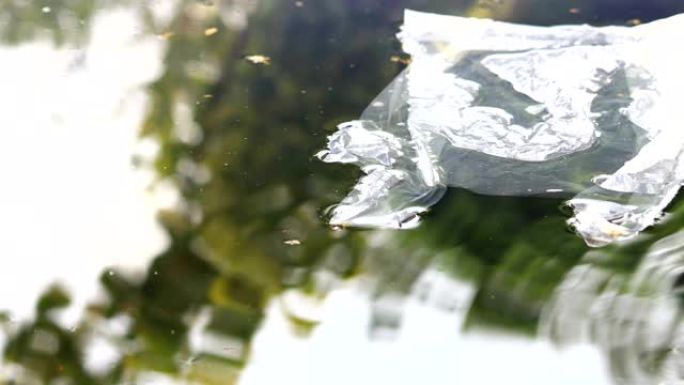 透明塑料袋在水面漂流，绿色自然反射，环境污染4k