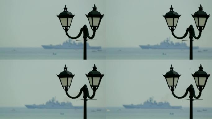 傍晚路堤上的老式灯笼和背景中的军舰