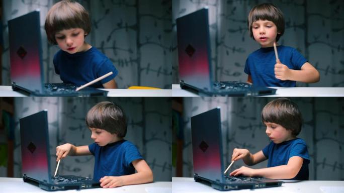 这个男孩坐在笔记本电脑的桌子旁，用铅笔折断了钥匙。