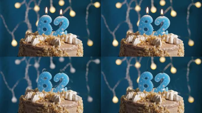 蓝色背景上有62号蜡烛的生日蛋糕。蜡烛吹灭了。慢动作和特写视图