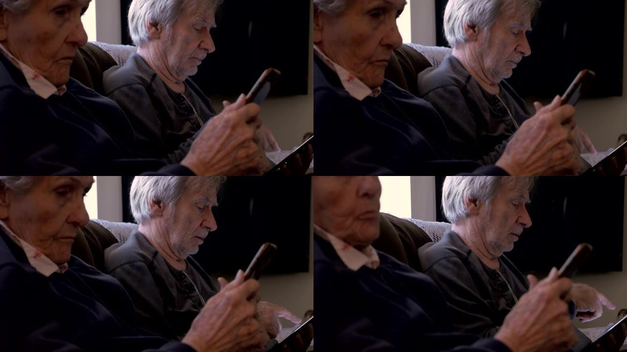 90岁的妇女和儿子看他们的移动设备，手机和平板电脑