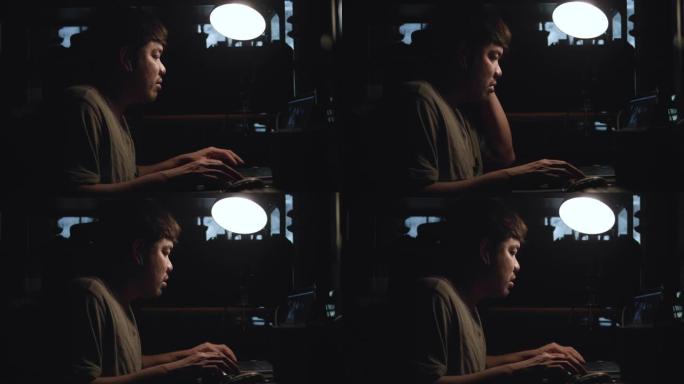 一个年轻人晚上坐在家里的笔记本电脑上工作