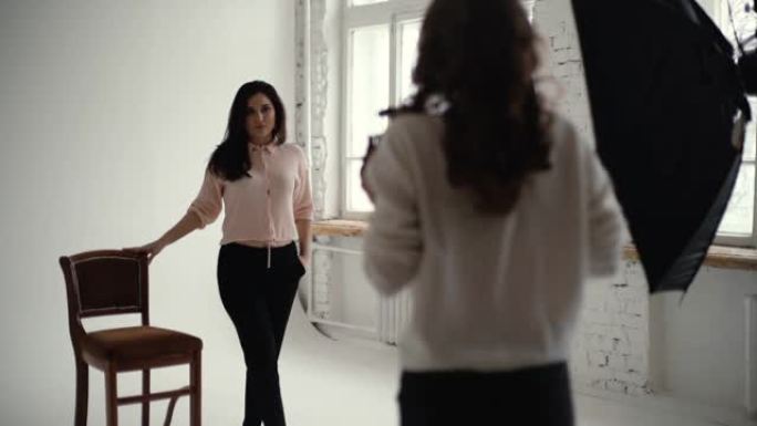 年轻女性模特在摄影棚为女摄影师摆椅子。