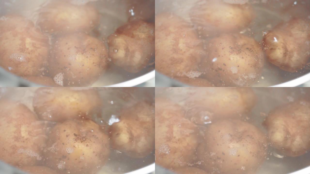 在煮沸的水煮熟土豆的过程。土豆在皮肤里。厨房概念