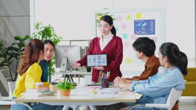 亚洲女性领导者手持数码平板电脑在商务会议团队上展示商业计划，亚洲女性项目经理在创意现代办公室展示移动