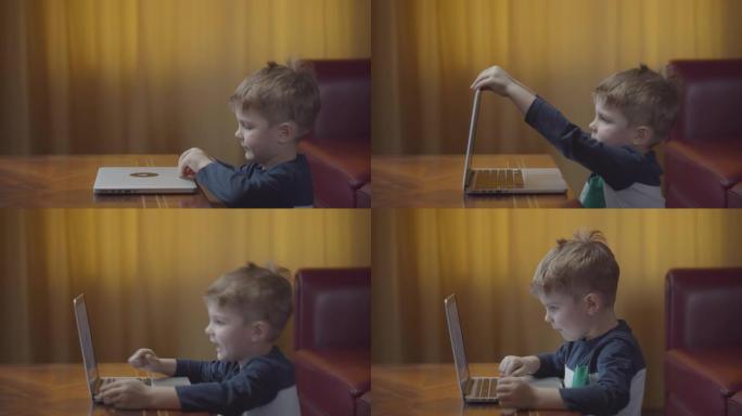 金发碧眼的学龄前男孩在笔记本电脑上打开和打字，微笑着看着电脑屏幕。孩子坐在桌旁在家在线学习。侧视图