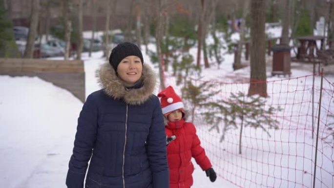 一名年轻女子和她的小儿子在山区度假活动公园的油管上玩得很开心。寒假概念