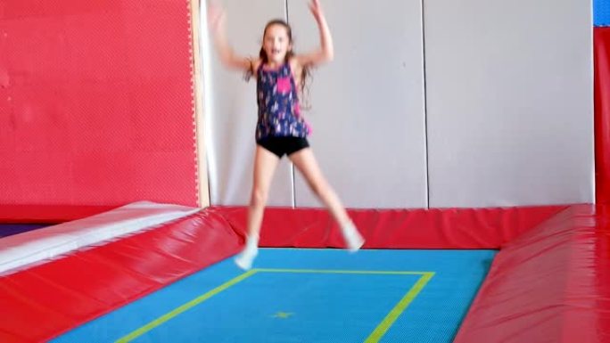 小女孩在游戏中心蹦床和蹦极上跳跃。