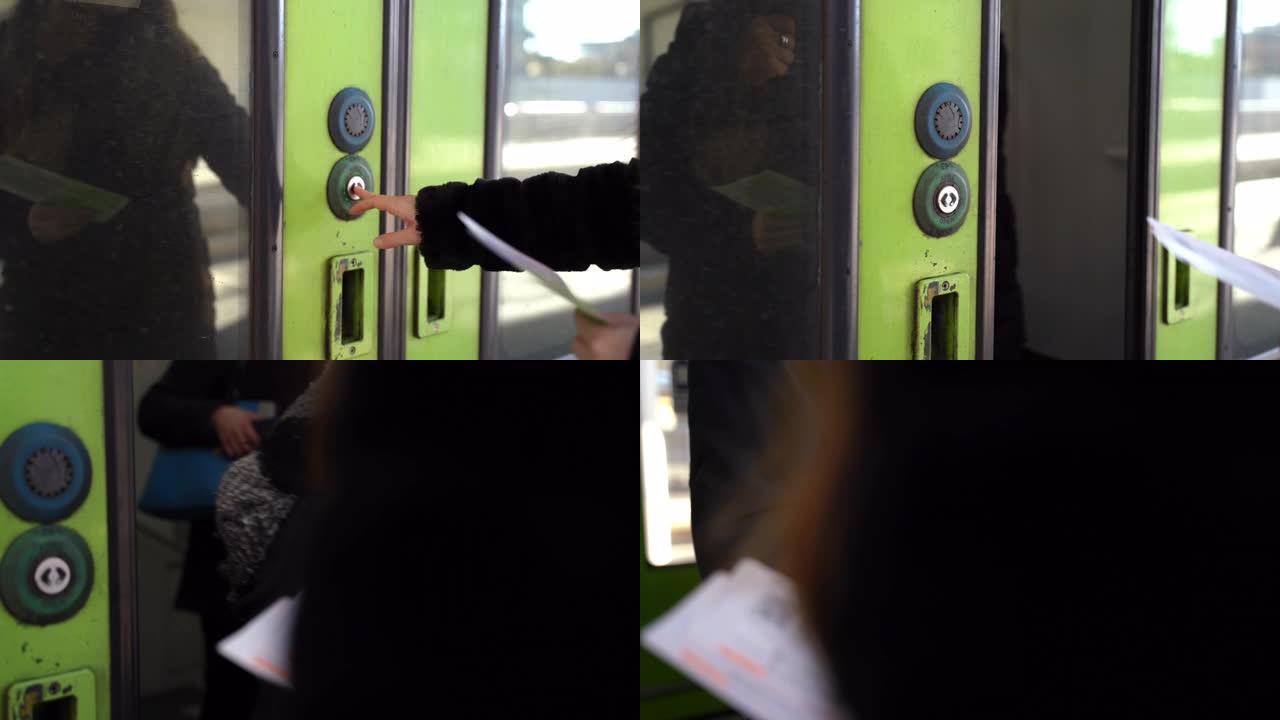 女孩的手的特写镜头按下火车门的绿色按钮在车站将其打开。等待列车到达和车门打开的女性乘客。公共交通中的
