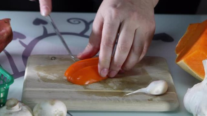 女人在厨房的木板上切成橙色的贝尔胡椒粉。女性手准备一份甜椒沙拉。健康饮食理念