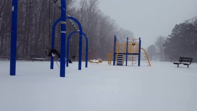 * 更明亮的版本 * 冬季降雪期间的儿童游戏公园。白天在地面上下雪的操场。