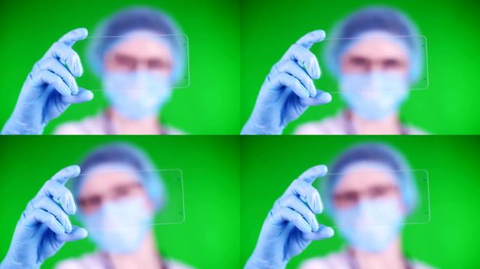 绿色背景。特写镜头，医生穿着医疗帽，口罩，蓝色医用手套，手持玻璃卡片，可以在上面放置广告，文字或视频