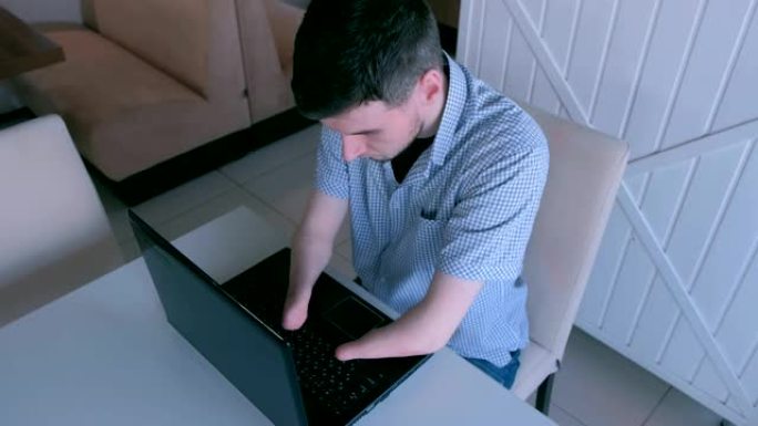 一个双手被截肢的残疾人在咖啡馆用笔记本电脑工作。