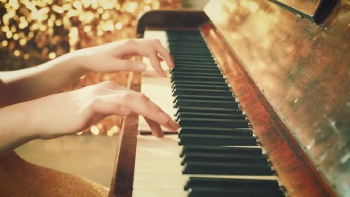 特写美丽的女性双手手指轻轻触摸黑白音乐键。音乐家演奏钢琴背景明亮闪亮的复古金色场景。棕色木制复古古董