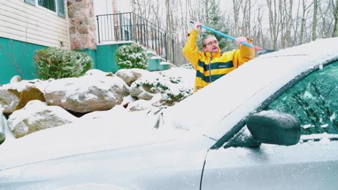 成熟的男人用扫帚从冰雪中刷汽车。